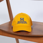 Yellow cap with 'Madonna University' logo on a wooden chair
