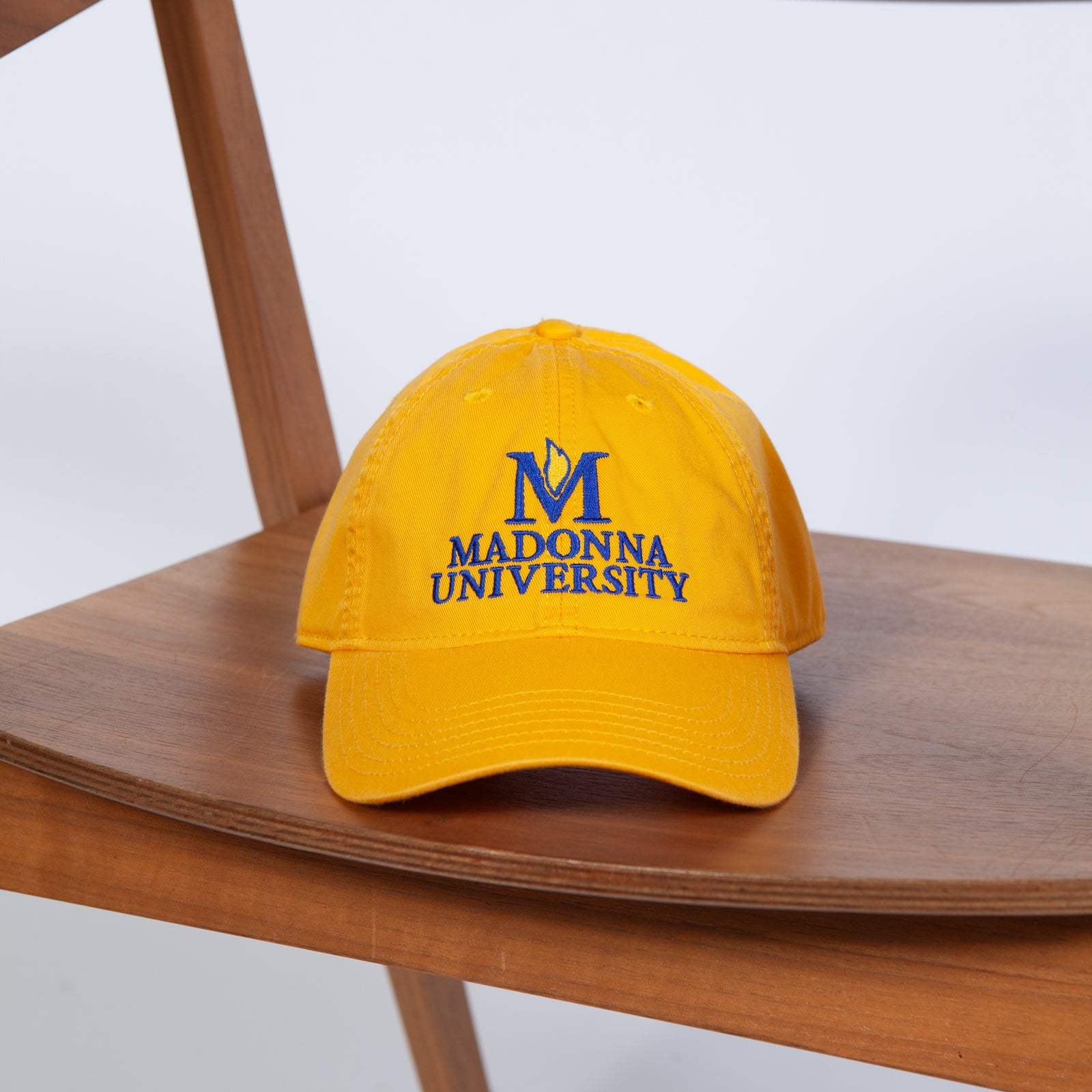 Yellow cap with 'Madonna University' logo on a wooden chair