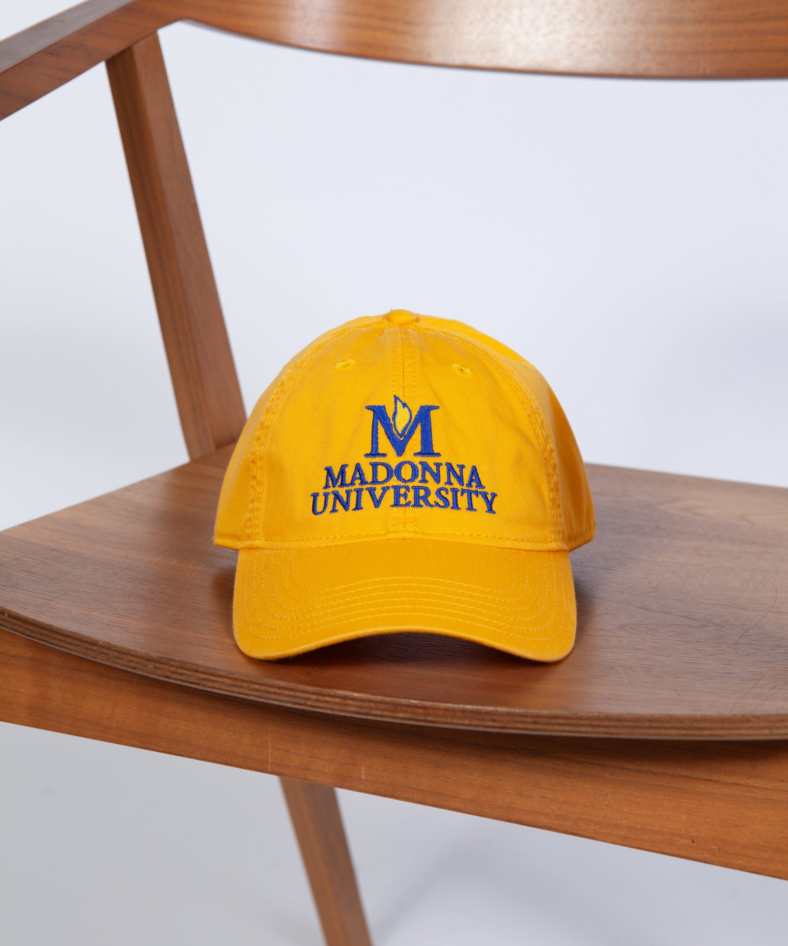 Yellow cap with 'Madonna University' logo on a wooden chair