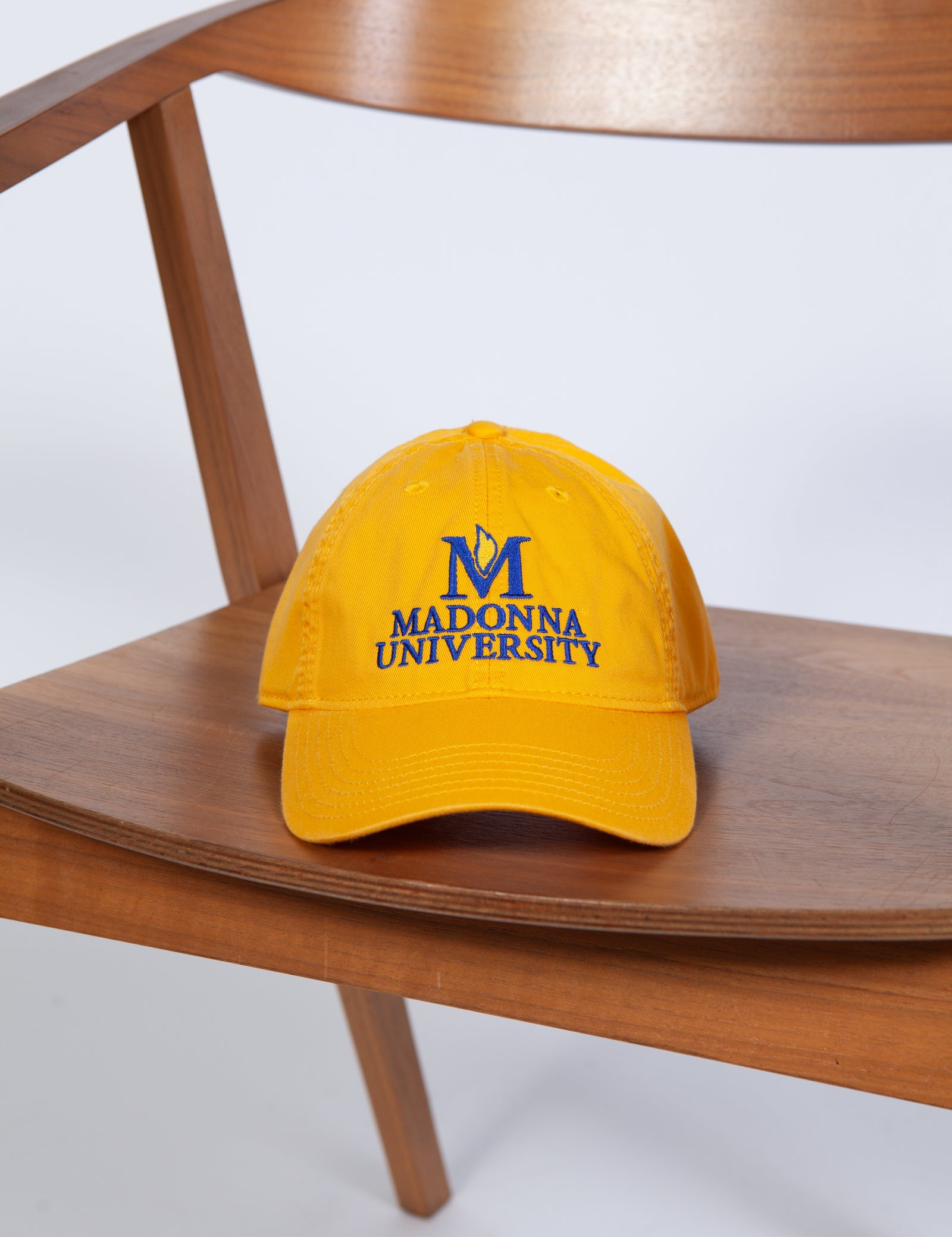 Yellow cap with 'Madonna University' logo on a wooden chair