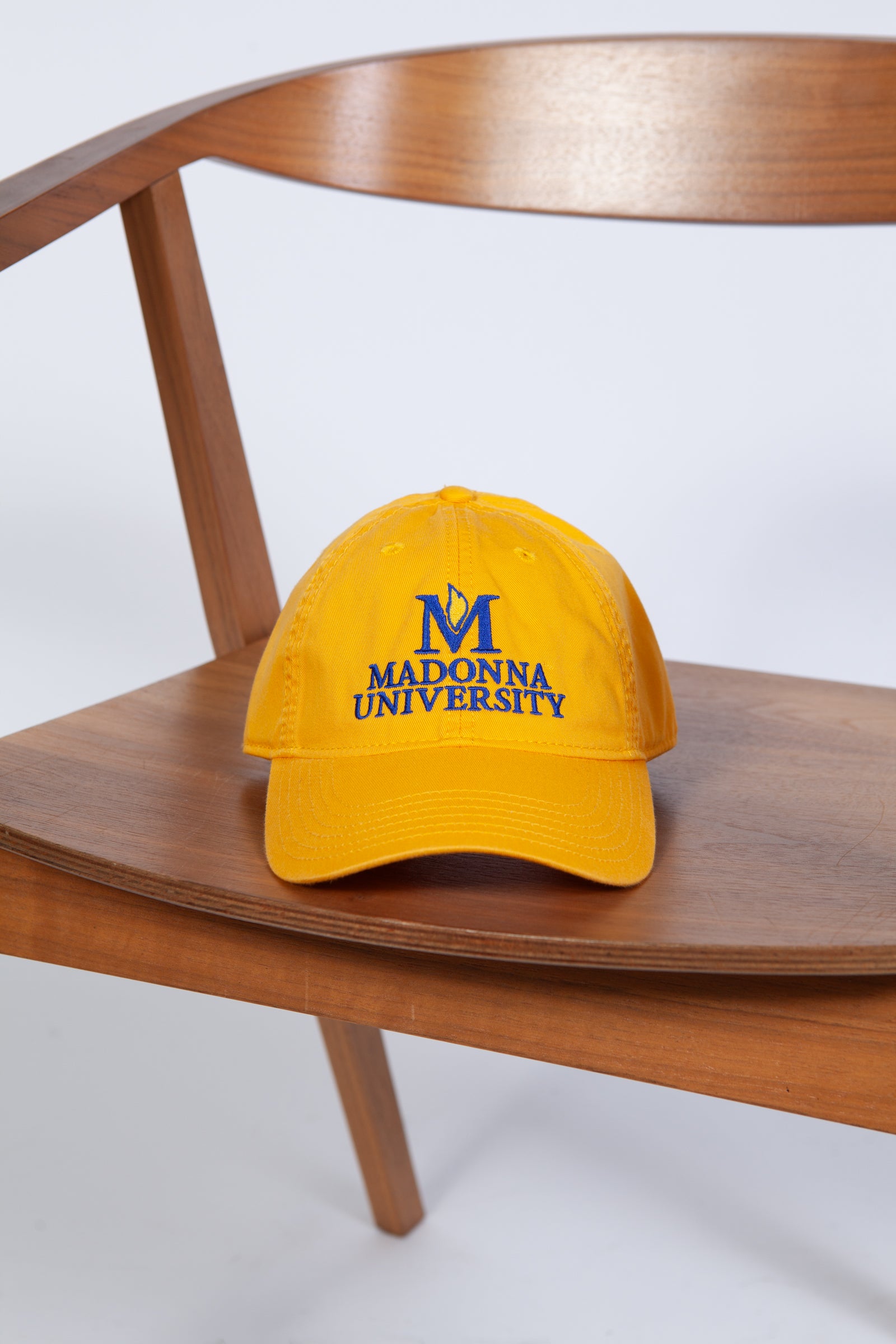 Yellow cap with 'Madonna University' logo on a wooden chair